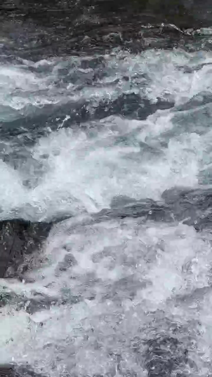 Acqua di fiume impetuosa su rocce scure