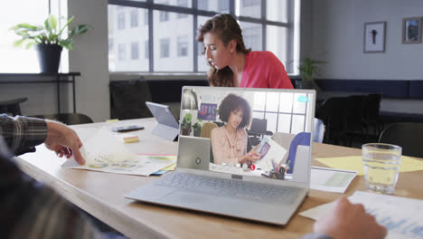 Caucasian-businessman-on-laptop-video-call-with-african-american-female-colleague-on-screen