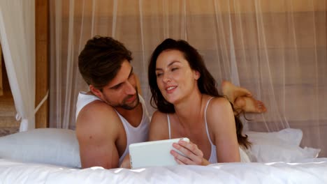 pareja feliz usando tableta digital mientras está acostada en la cama 4k
