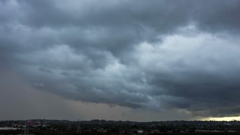 dark and moody time lapse of massive cloud formation with wall of rain pouring and passing above the city