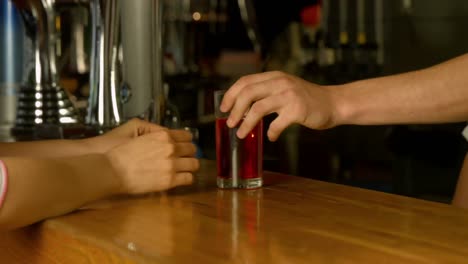 mujer siendo servida una bebida en el bar