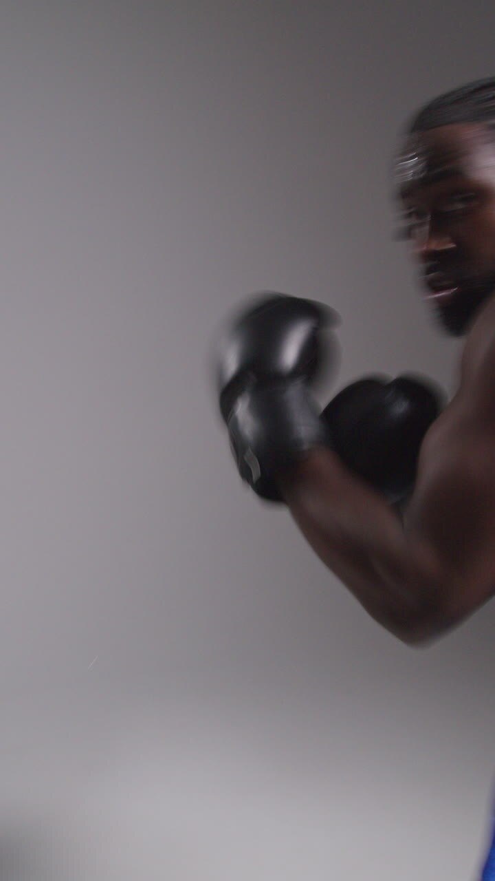 Video verticale, ripresa POV in tempo reale in studio di un pugile che indossa guantoni da boxe in un incontro di boxe, che sferra pugni verso la telecamera 2