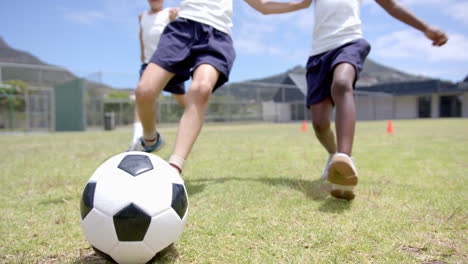 playing soccer on school field, children running and kicking ball energetically