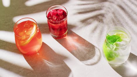 Close-up-of-drinks-with-orange,-raspberry-and-lemon-over-shadow