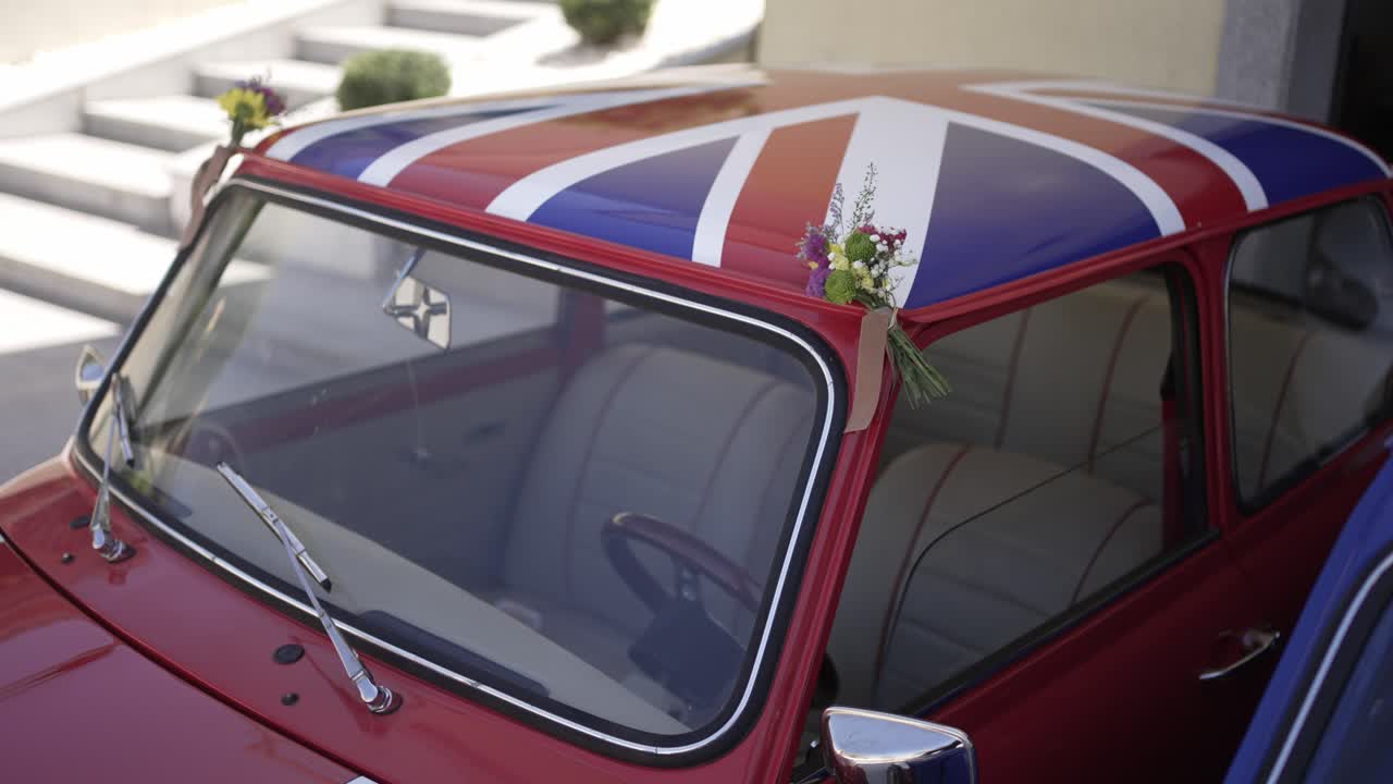 Red Mini Cooper with a Union Jack roof adorned with floral wedding decorations