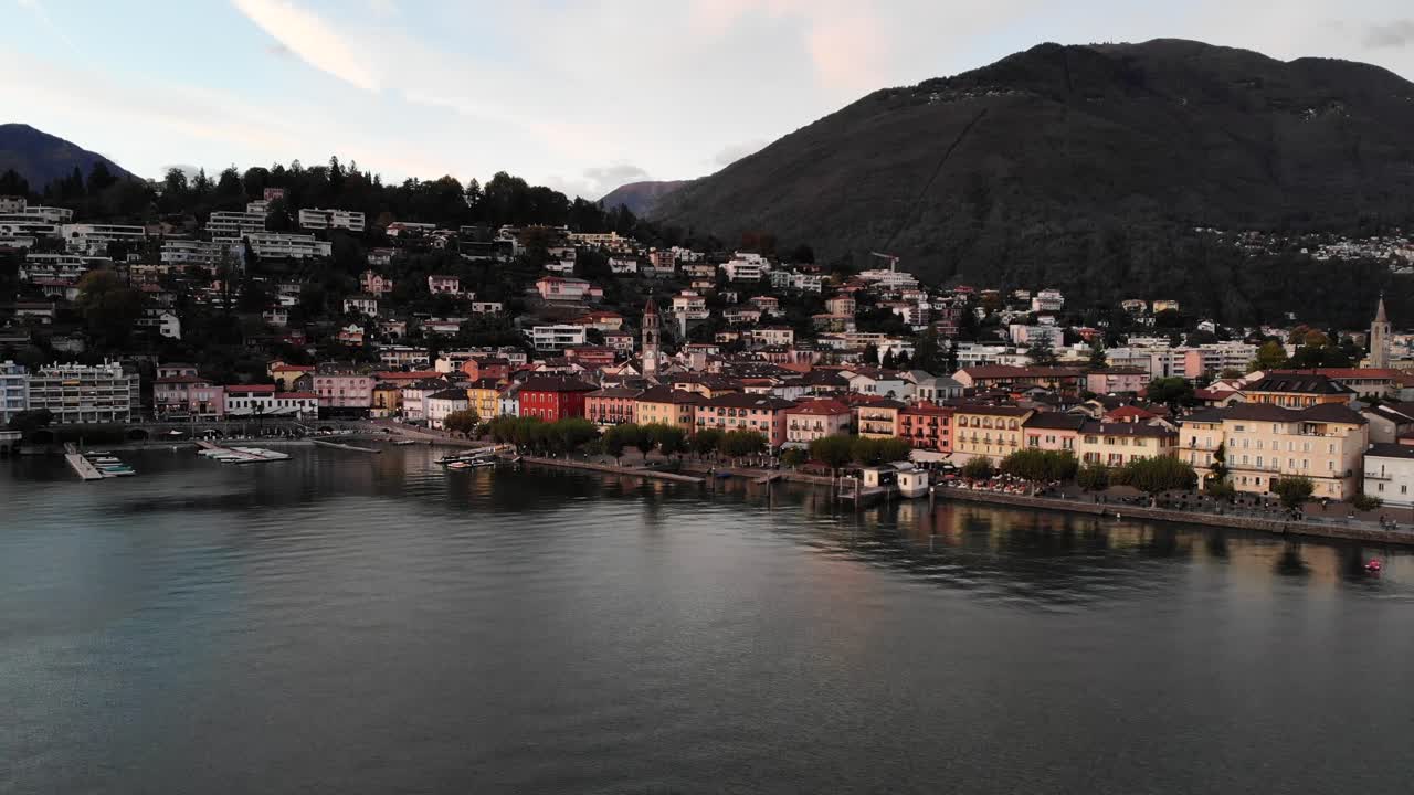 sobrevuelo aéreo sobre las aguas del lago maggiore a lo largo de la costa de ascona, ticino en la suiza italiana al final de un día de verano con casas coloridas y la torre de la iglesia a la vista