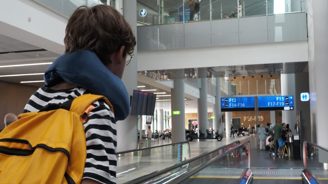 Boy with backpack and neck pillow at an airport