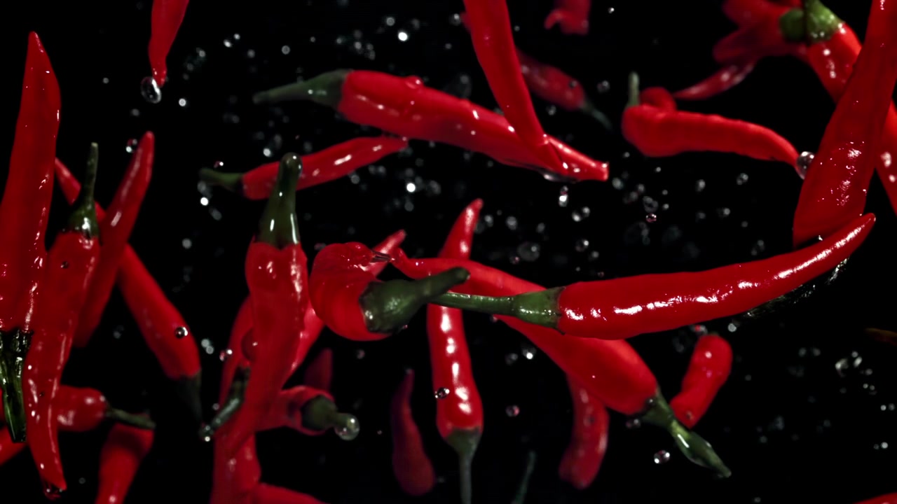 Vibrant Red Chili Peppers and Water Droplets Falling in Slow Motion