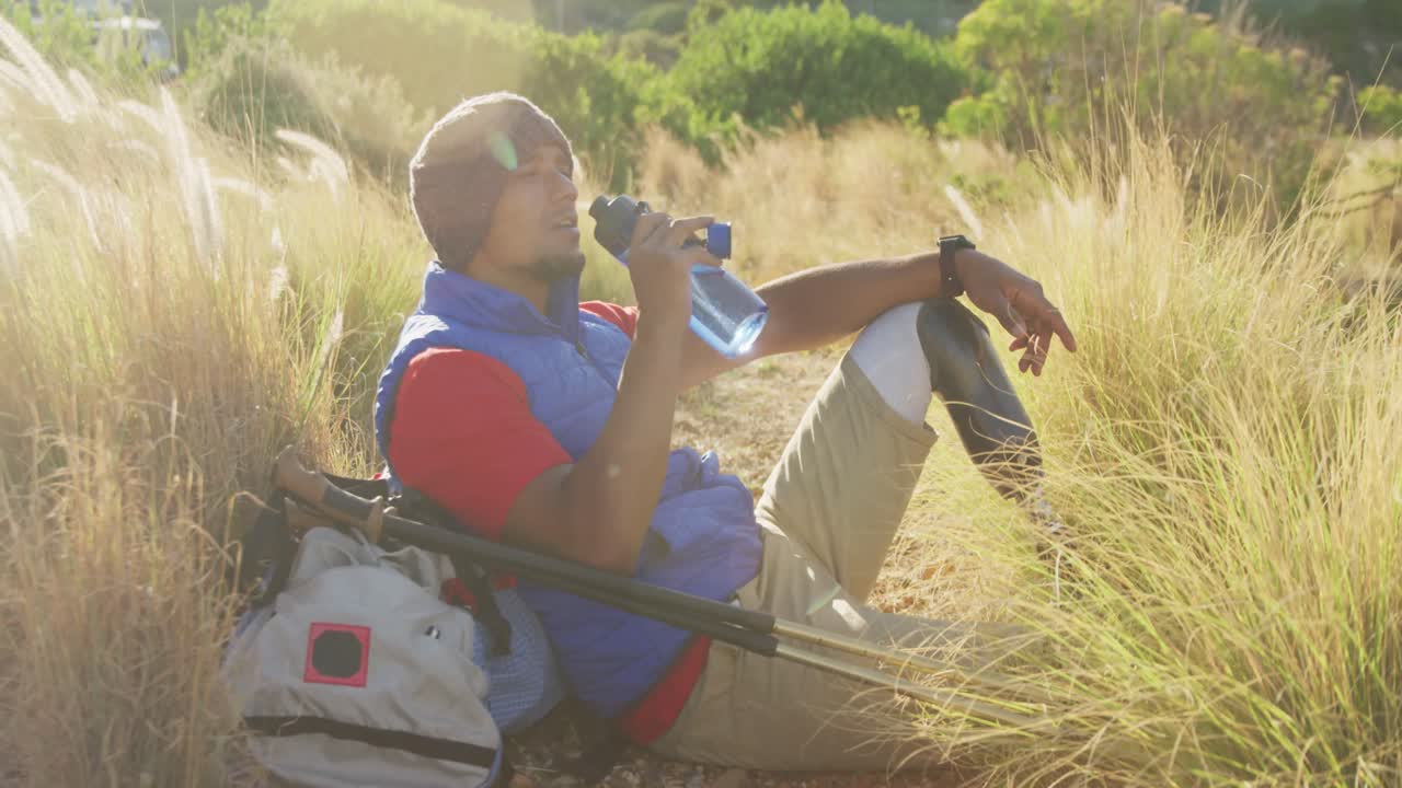 의족 을 가진 스포츠적 인 혼합 인종 의 남자 가 물 을 마시고 있다