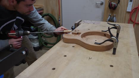 craftsman paying attention to detail when drilling hole into musical instrument