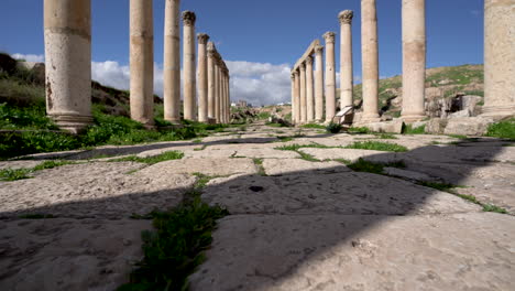 toma en ángulo bajo de un largo camino recto de piedra de pilares corintios bien conservados en ruinas romanas en jerash