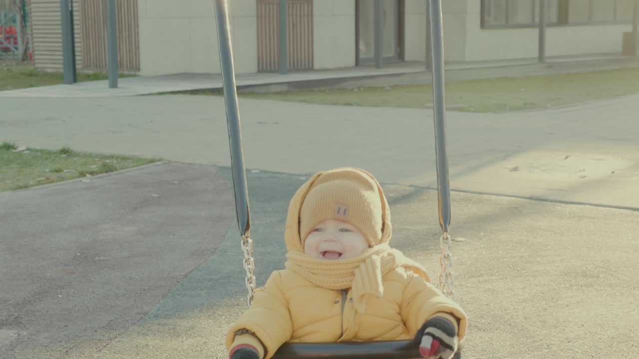Baby playing on a swing in the park