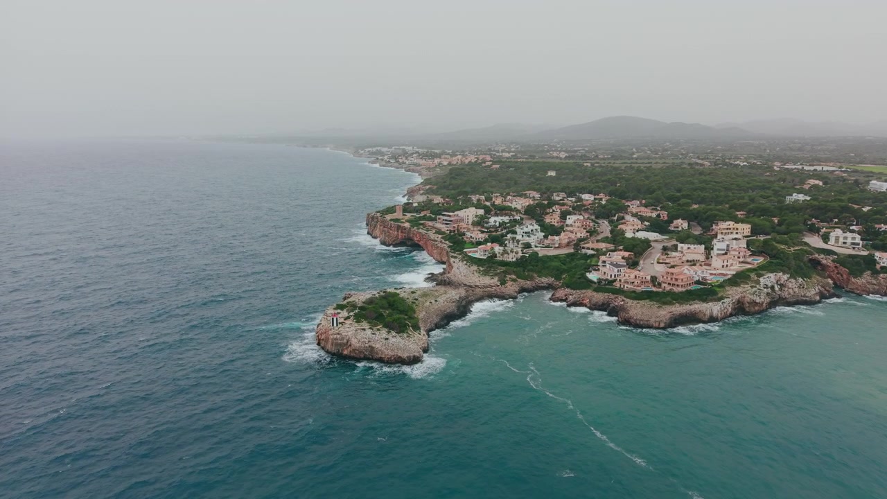 Veduta aerea di una città costiera con faro su una penisola rocciosa