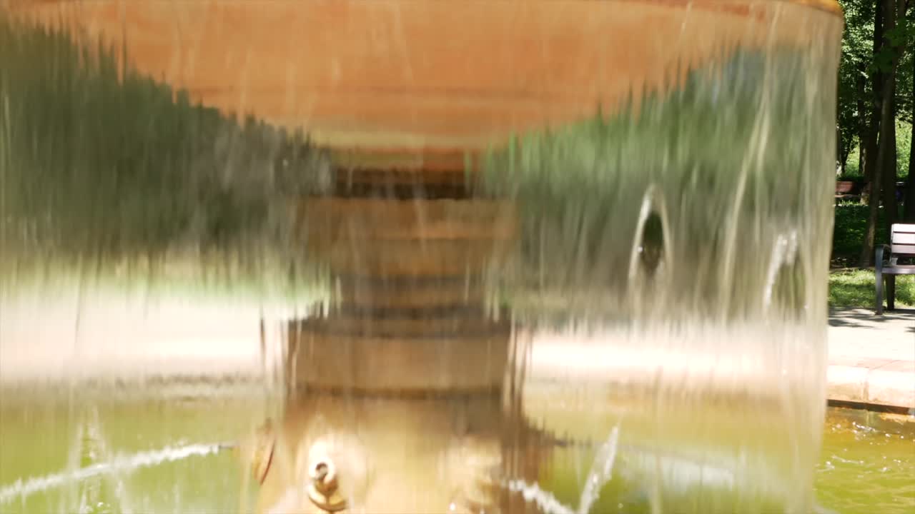 A small fountain with water in the summer park - a place of rest from the heat