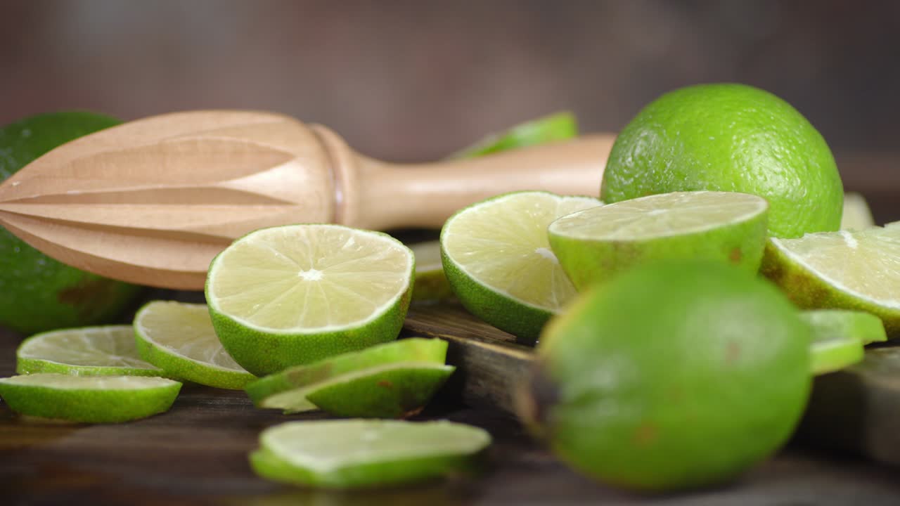 The slices of fresh lime on a wooden table slowly rotate.