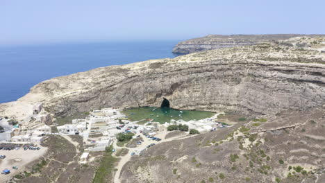 Ciudad-Portuaria-De-La-Cueva-De-Dwerja-Con-Barcos-Debajo-De-Un-Acantilado-Rocoso,zoom-Aéreo