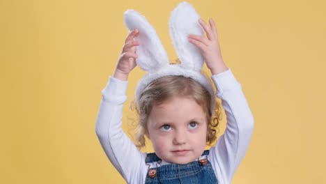 happy little girl with ears on his head stroking the easter bunny on the table with a cake in the kitchen. a little girl celebrates easter. traditional religious holiday of easter. vertical video