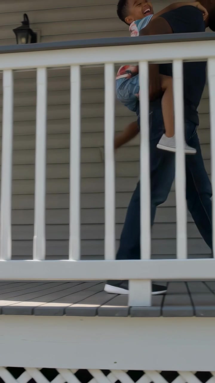 Video verticale: Uomo adulto che avanza portando in braccio un bambino che ride attraverso il portico, ringhiera con maschera.
