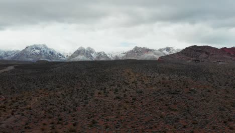 Aerial-drone-flight-up-with-snowcapped-mountains-in-the-background