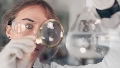 científica femenina examina un líquido en un tubo con una lupa
