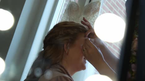 artista de maquillaje trabaja en los ojos de la novia con el vestido de novia en el fondo, vista lateral