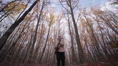 guy playing by the guitar in autumn background with yellow leaves in the park