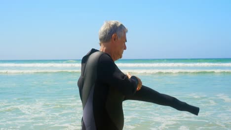 Seitenansicht-Eines-Aktiven-älteren-Kaukasischen-Männlichen-Surfers-Im-Neoprenanzug-Am-Strand-4k