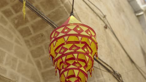 Colourful-red,-yellow-fabric-patio-lantern-in-alley-as-seen-from-below