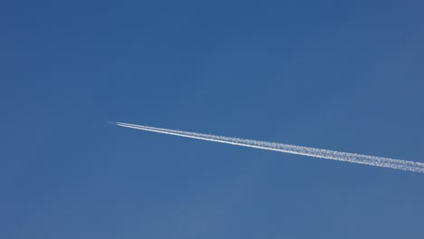 el avión está haciendo nubes mientras vuela sobre el cielo azul