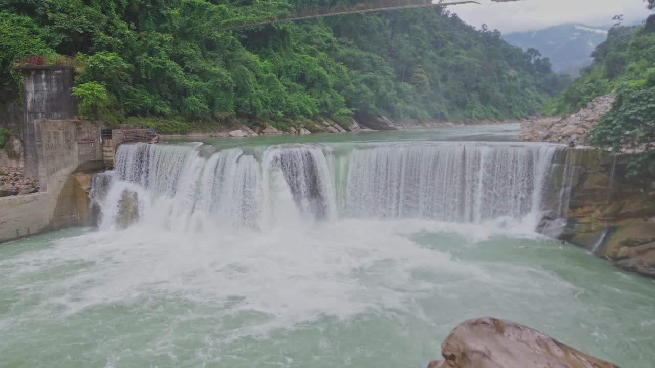 Một cảnh trên không tuyệt đẹp về một thác nước tuyệt đẹp đổ xuống những ngọn núi xanh tươi, thể hiện vẻ đẹp hoang sơ của thiên nhiên, dòng nước chảy và phong cảnh thanh bình