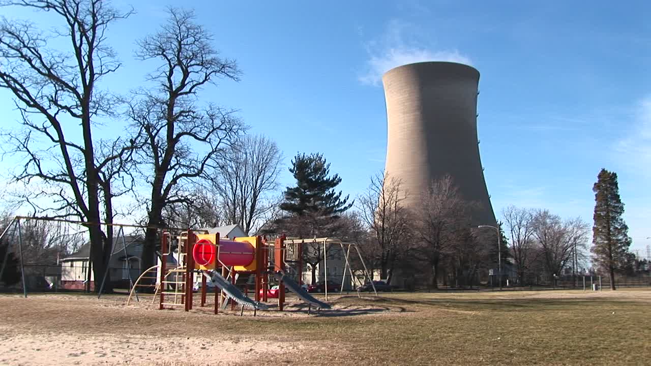 전경에는 원자력 발전소가 배경에 있는 어린이의 다채로운 놀이터가 보입니다.