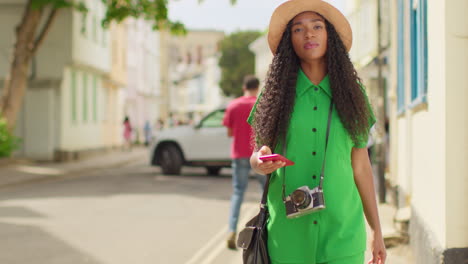 female tourist with camera on vacation in oxford uk exploring city walking along holywell street using mobile phone for directions and information 2