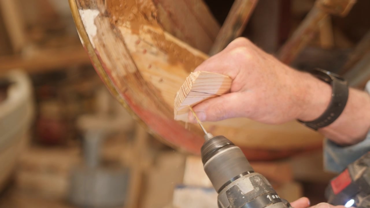Shipwright drilling pilot hole on hull plank for fastening