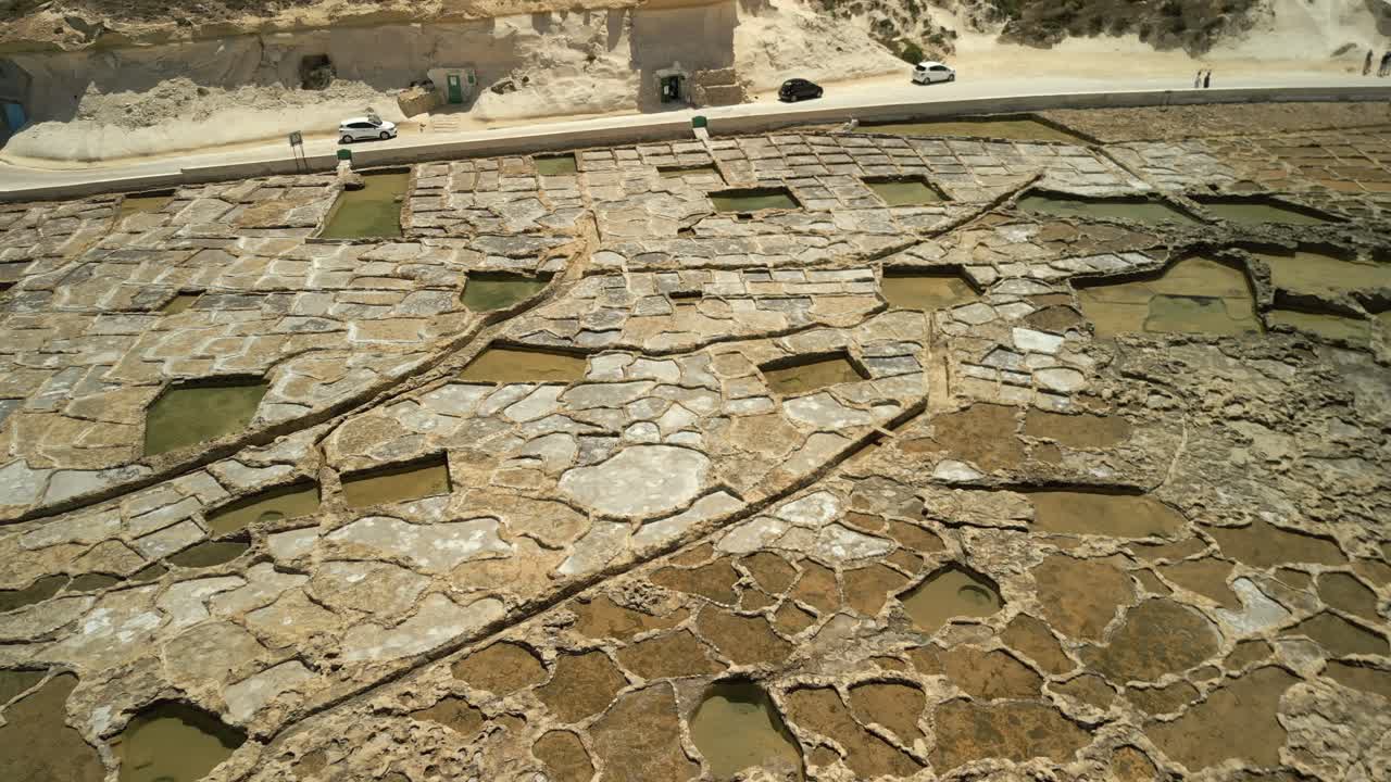 imágenes aéreas de las llanuras de sal de xwejni en gozo, malta que muestran salinas y una carretera en la parte posterior