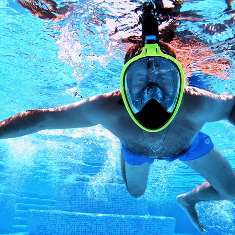 underwater background of a swimming pool. a man in yellow mask swimming inside the clear blue water of a pool.