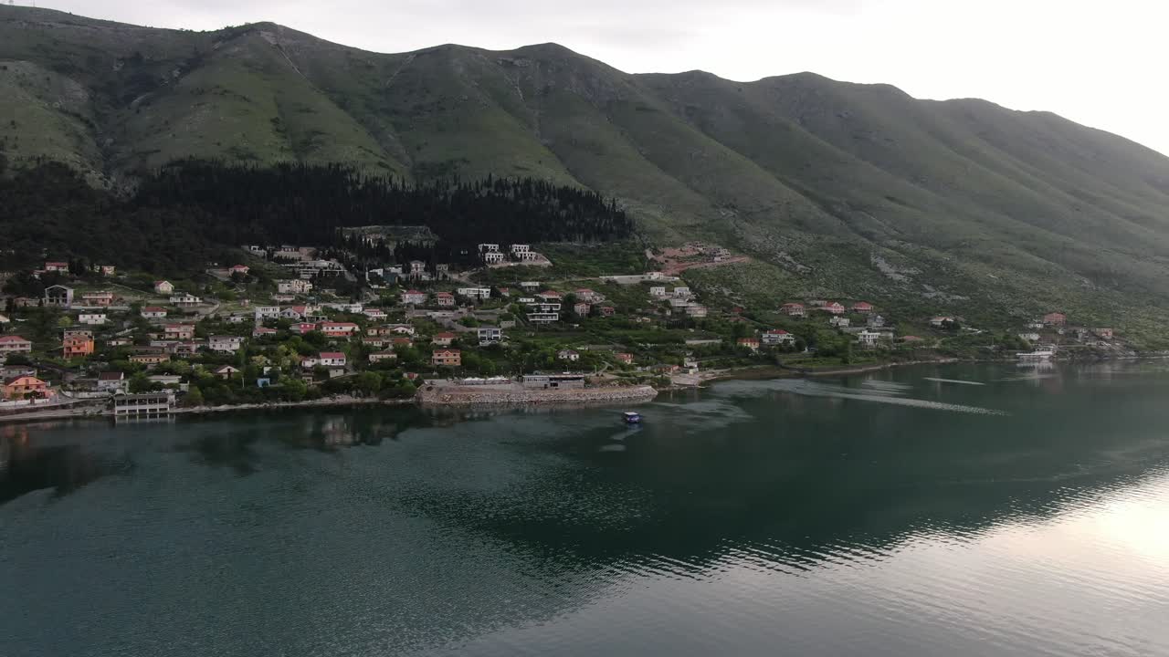 Drone view in Albania flying over Shkod&euml;r lake in Pogradec on cloudy day with green mountains on the back horizontal move