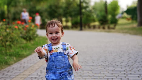 lovely excited baby boy holding a ball. kid throws the ball and turns away. summer fun in the park.