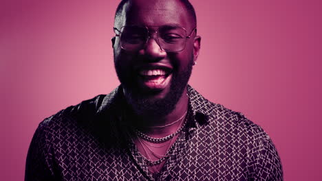 happy afro guy laughing indoors. male person giggling on pink background