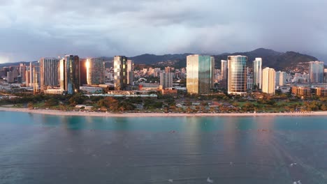 Wide-rising-aerial-dolly-shot-of-run-reflections-off-buildings-in-Honolulu-on-the-island-of-O'ahu,-Hawaii