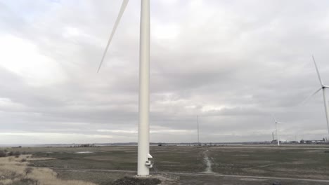 sustainable electrical wind turbines spinning on england farmland rising aerial to blades rotating