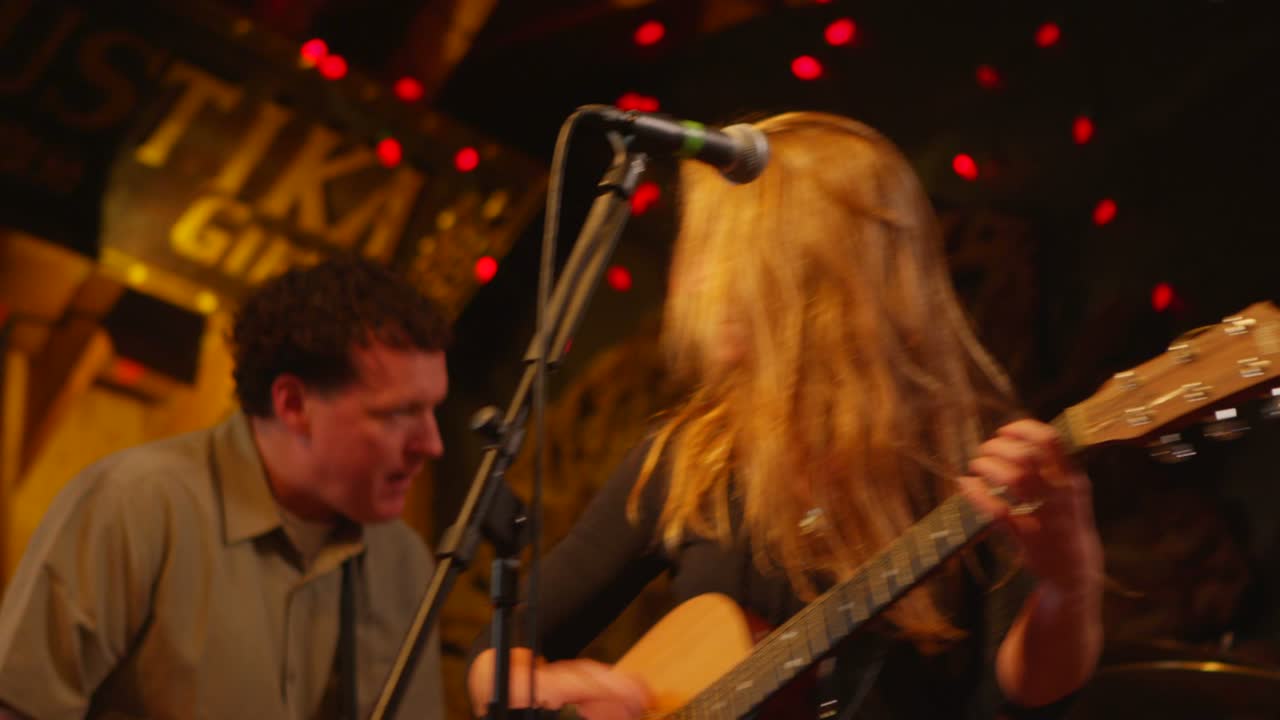 여자가 기타를 치고 마이크에 대고 노래한다