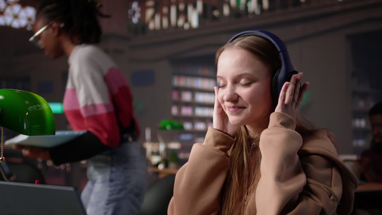 Vertical video female student listening to favorite songs and solving a school assignment