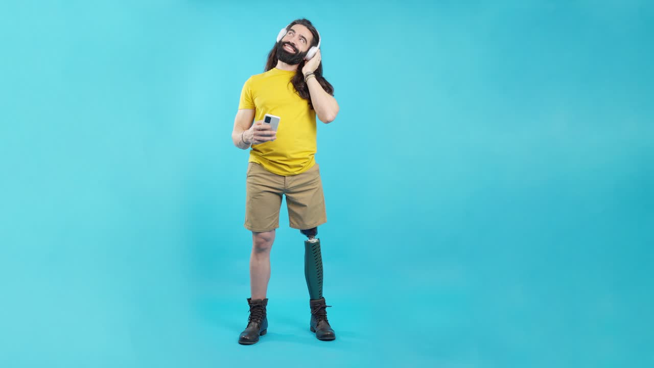 Man with prosthetic leg listening to music on headphones and holding a smartphone