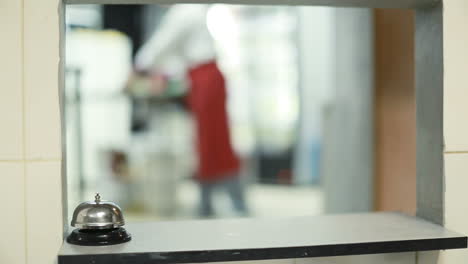 Cook Man Pressing A Bell Indoor. Chef ringing bell at order in the commercial kitchen