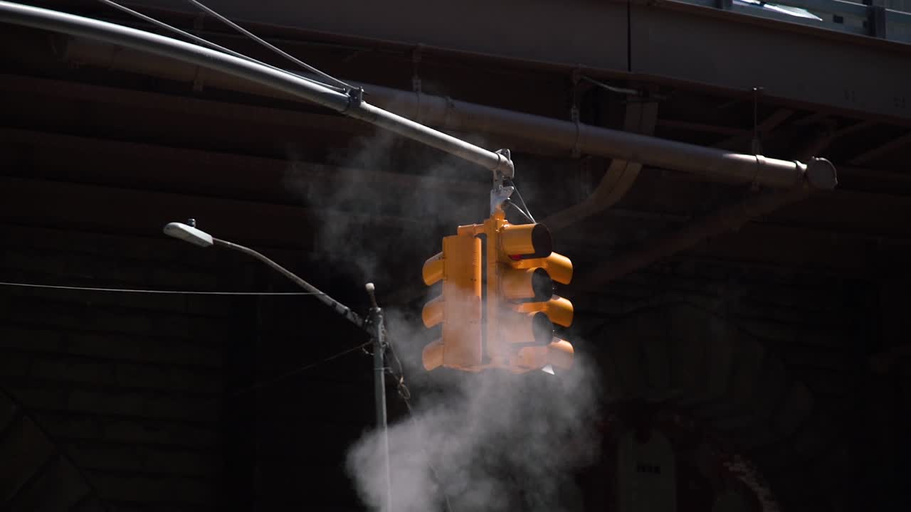 Yellow Traffic Light in a Dark Background with Steam coming out of the Streets in New York City.