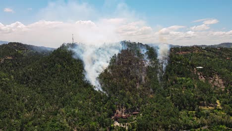 Fire-in-the-mountains,-air-pollution,-nature-and-wildlife-destruction-by-human-being,-stunning-smoke-trail-in-the-sky,-aerial-view-of-a-burning-mountain