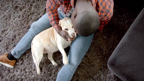 Feliz-Hombre-Afroamericano-Sentado-En-El-Suelo-En-Casa,-Acariciando-A-Su-Perro-Mascota,-Cámara-Lenta