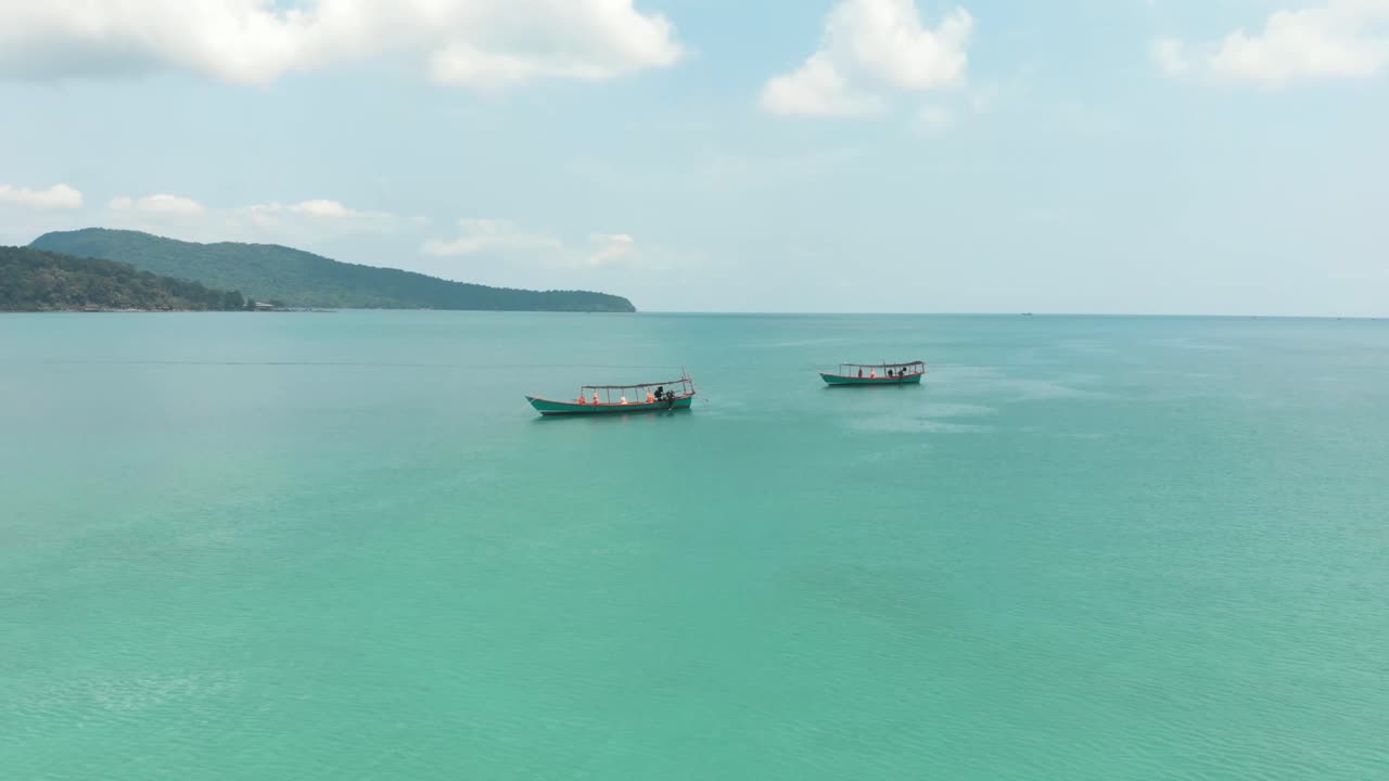 Barche da pesca ormeggiate e in riposo su splendide acque azzurre cristalline a Saracen Bay a Koh Rong Sanloem, Cambogia - Ripresa aerea orbitale a bassa angolazione.