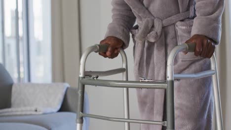 mid section of senior man using zimmer frame to walk at home