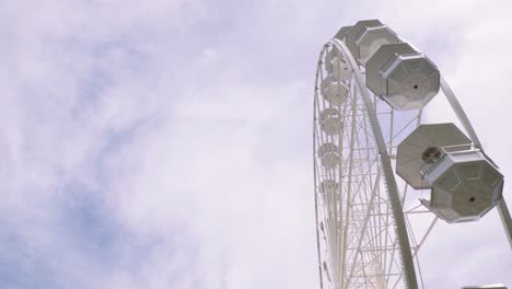 Close-up-views-of-a-Ferris-wheel-rotating-against-a-blue-sky-with-some-clouds